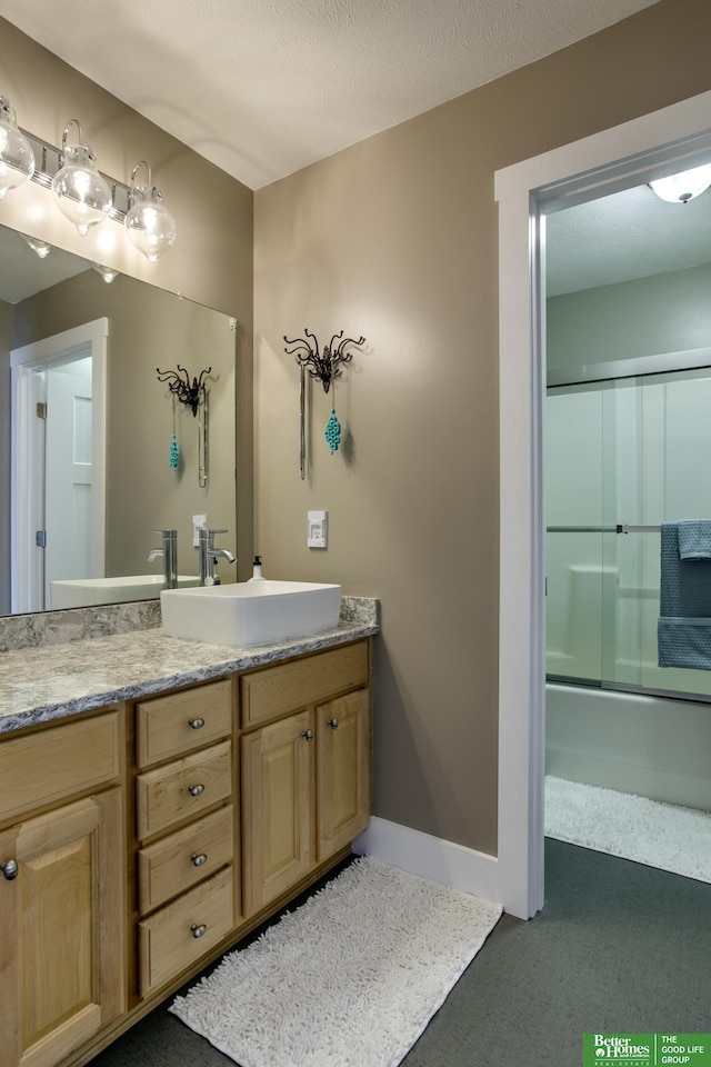 bathroom featuring bath / shower combo with glass door, baseboards, and vanity
