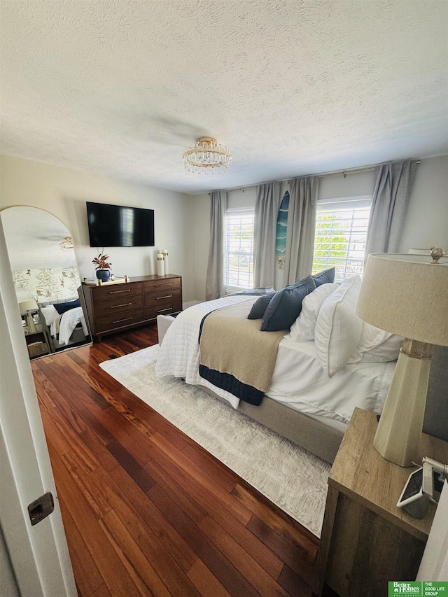 bedroom featuring dark wood-style flooring, a textured ceiling, and arched walkways