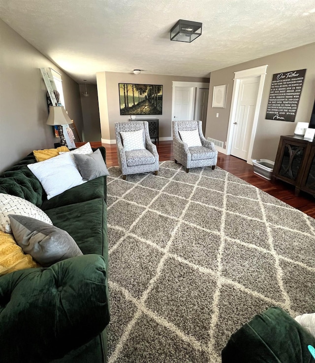 living room with a textured ceiling, wood finished floors, and baseboards