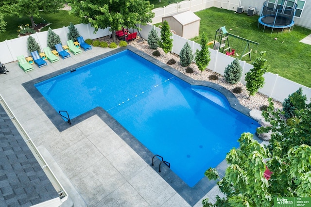 view of pool with a yard, a fenced in pool, a patio, a trampoline, and a fenced backyard