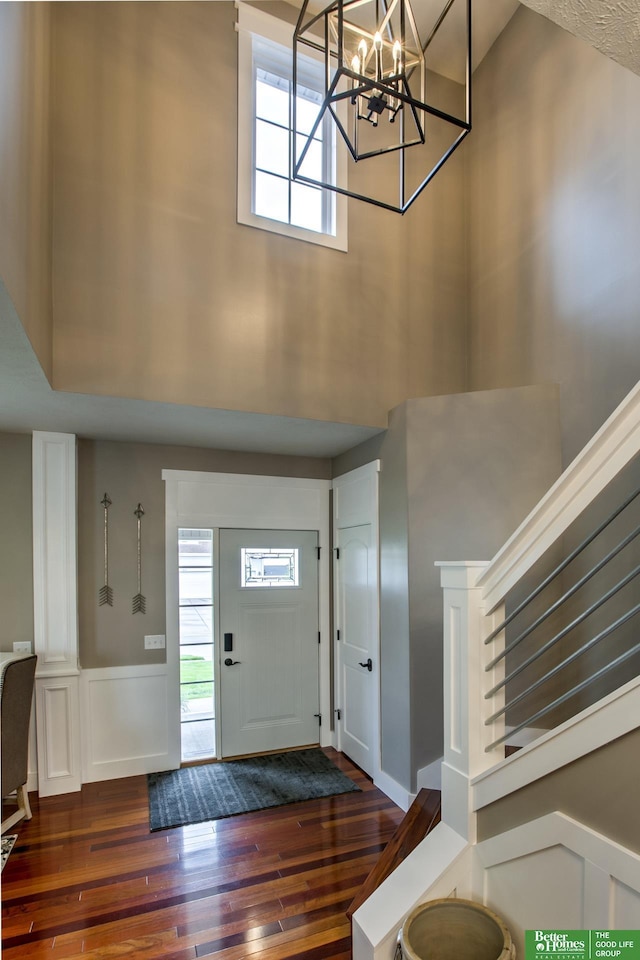 foyer entrance with hardwood / wood-style flooring, a towering ceiling, and plenty of natural light