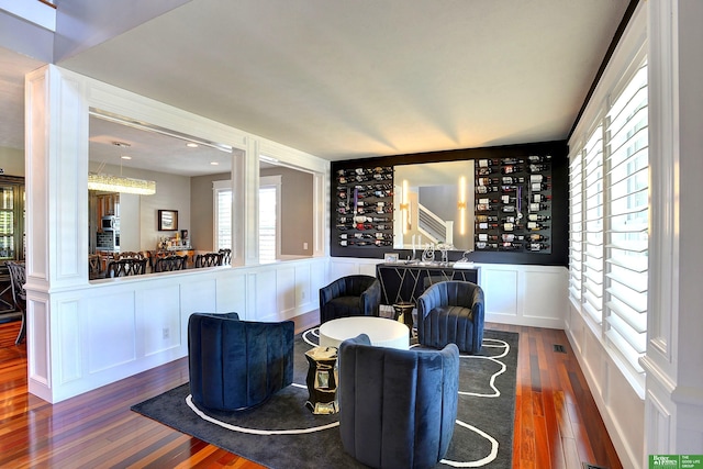 interior space featuring visible vents, a decorative wall, wainscoting, and dark wood-style floors