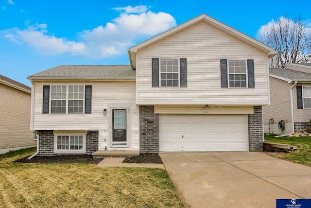 tri-level home with concrete driveway, a front lawn, brick siding, and a garage