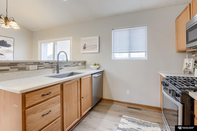 kitchen featuring a sink, backsplash, a wealth of natural light, and appliances with stainless steel finishes