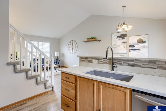 kitchen with a sink, stainless steel dishwasher, light countertops, light wood-style floors, and tasteful backsplash