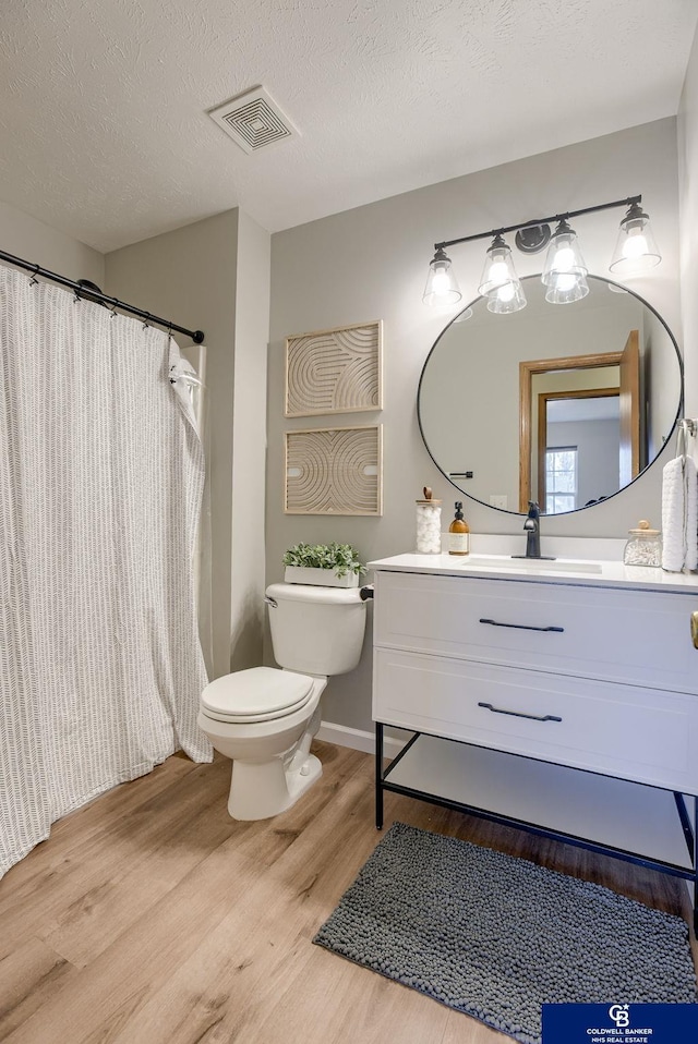 bathroom with toilet, wood finished floors, a shower with shower curtain, visible vents, and vanity