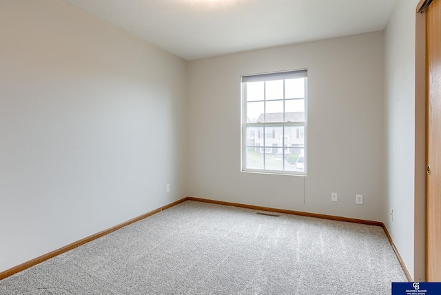 spare room featuring carpet flooring, visible vents, and baseboards