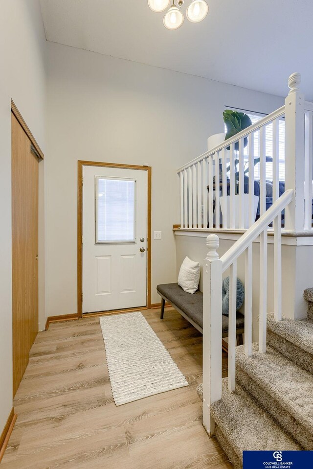 entryway with light wood-style flooring, baseboards, and stairs