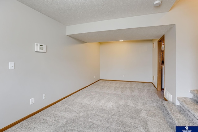 finished basement featuring stairway, a textured ceiling, carpet flooring, and baseboards