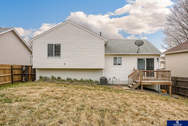 back of property with cooling unit, fence, a wooden deck, a lawn, and roof with shingles
