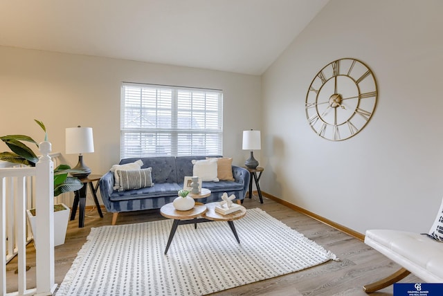 living room featuring vaulted ceiling, baseboards, and light wood-type flooring