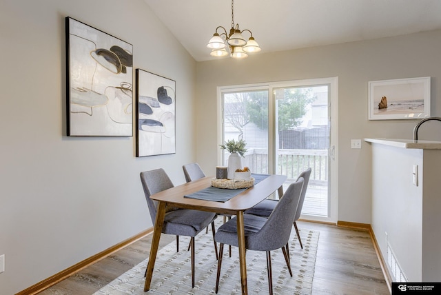 dining room featuring vaulted ceiling, an inviting chandelier, baseboards, and light wood-type flooring
