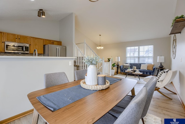 dining space featuring an inviting chandelier, light wood-style flooring, and baseboards