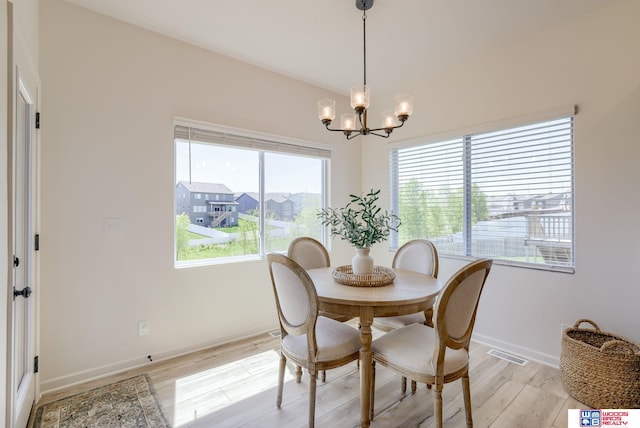dining area featuring light wood finished floors, visible vents, baseboards, and a notable chandelier