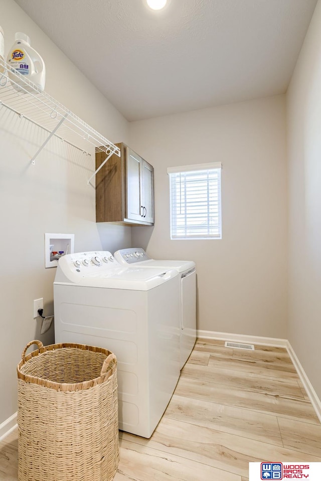 laundry room with cabinet space, independent washer and dryer, light wood-type flooring, and visible vents