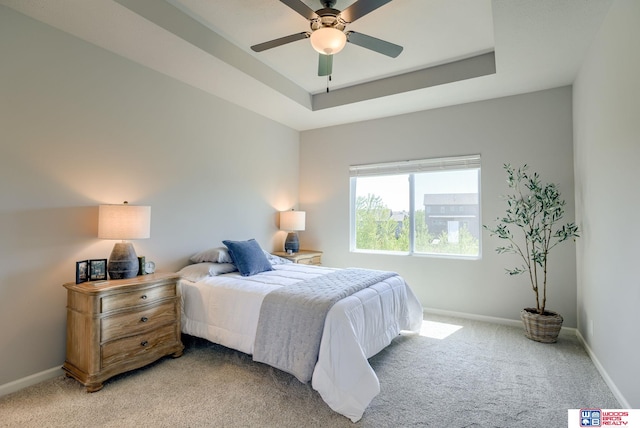 bedroom with baseboards, a raised ceiling, ceiling fan, and light colored carpet