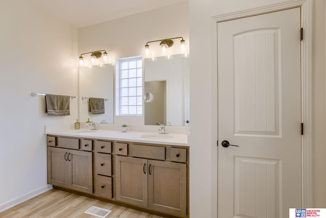 full bathroom featuring a sink, double vanity, visible vents, and wood finished floors