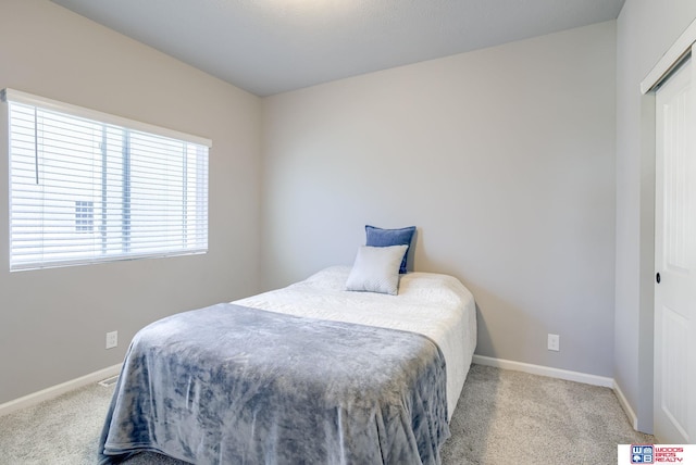 carpeted bedroom featuring baseboards and a closet