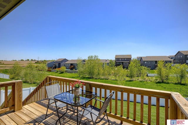 wooden deck with a lawn, outdoor dining area, and a residential view