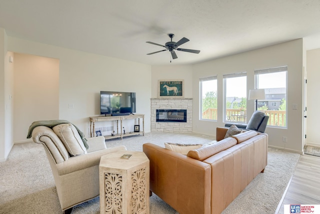 living room with light wood-style floors, a fireplace, baseboards, and ceiling fan