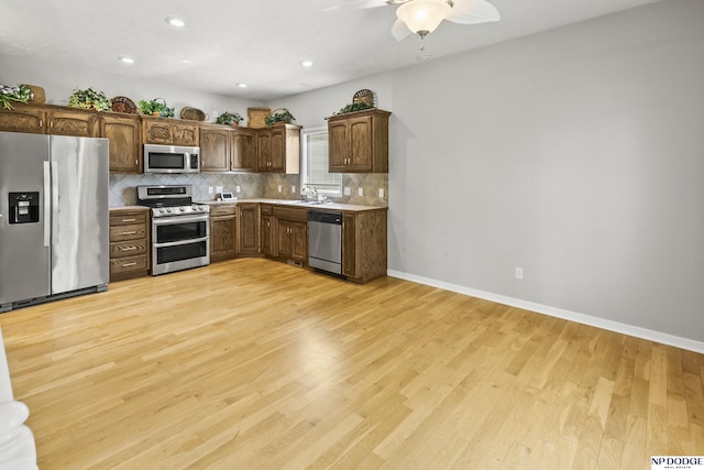 kitchen with light wood-type flooring, stainless steel appliances, tasteful backsplash, and a sink