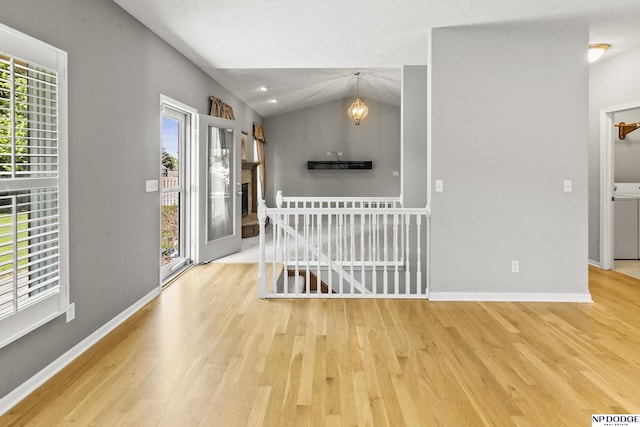 spare room with an inviting chandelier, plenty of natural light, and wood finished floors