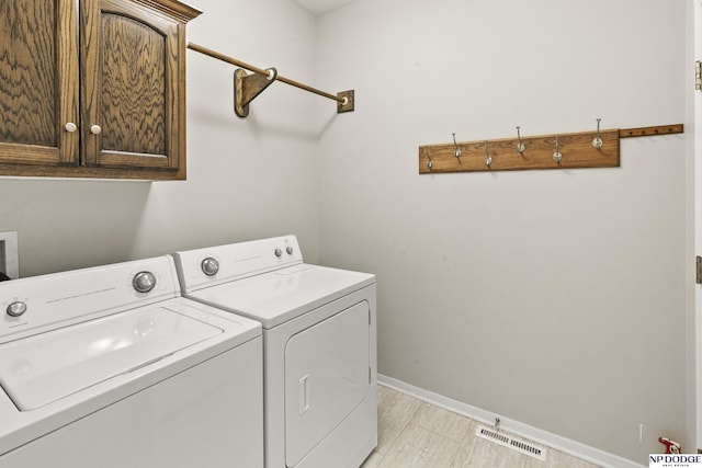 laundry area with washing machine and clothes dryer, baseboards, visible vents, and cabinet space