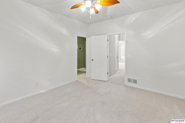 unfurnished room featuring light colored carpet, baseboards, a ceiling fan, and visible vents