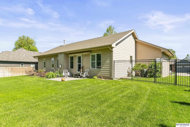 back of property featuring a shingled roof, a patio, a lawn, and a fenced backyard
