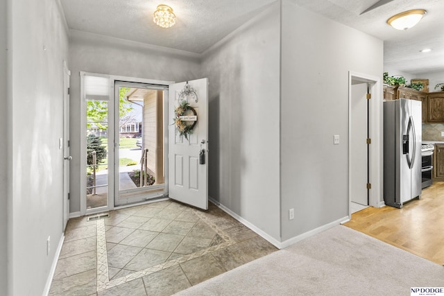 entrance foyer with a textured ceiling, baseboards, and visible vents