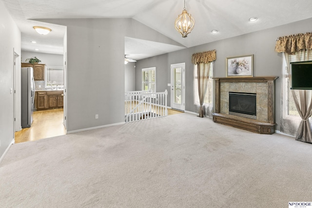 unfurnished living room with lofted ceiling, light carpet, baseboards, and a notable chandelier