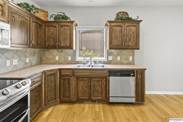 kitchen featuring light wood-type flooring, stainless steel appliances, visible vents, and a sink