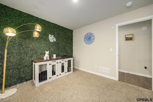 interior space featuring visible vents, baseboards, an accent wall, and carpet floors