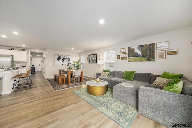 living area with baseboards, light wood-style floors, and recessed lighting