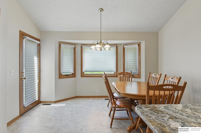 dining space with a chandelier, baseboards, and a textured ceiling