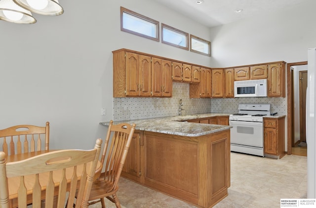 kitchen with white appliances, a high ceiling, a peninsula, brown cabinetry, and a sink