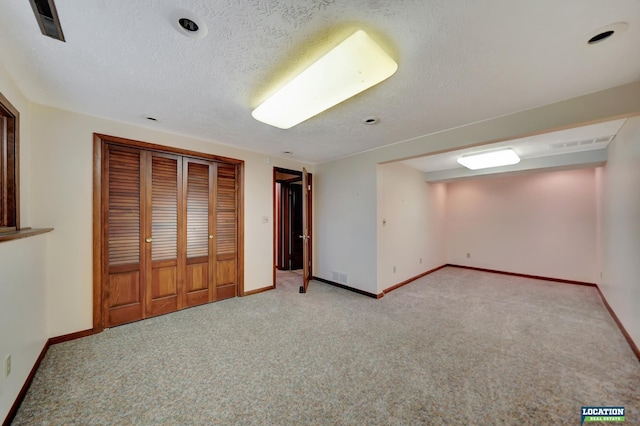 unfurnished bedroom featuring baseboards, a textured ceiling, visible vents, and light colored carpet