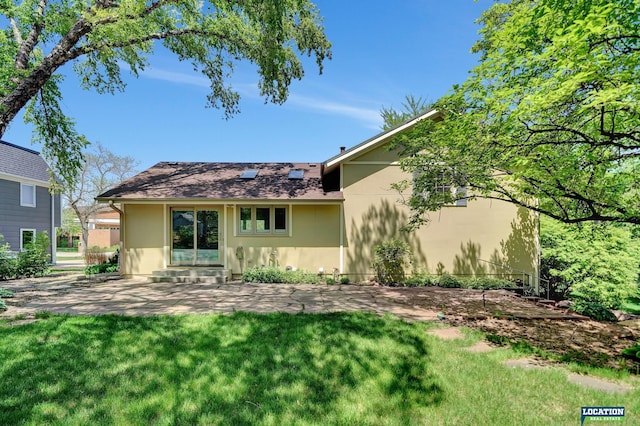 back of house with stucco siding, a lawn, and a patio area