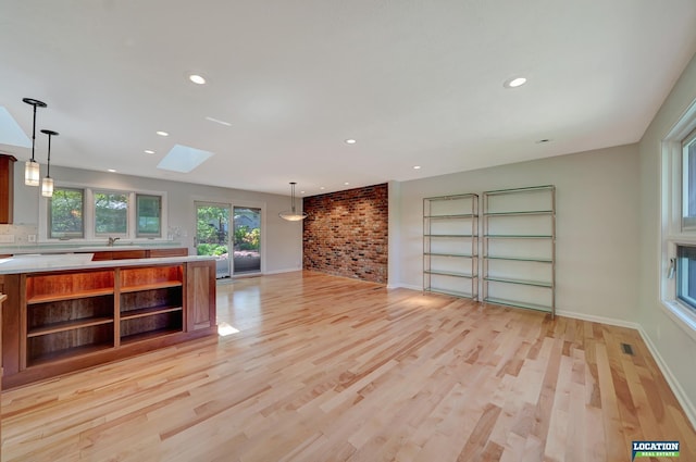 unfurnished living room with baseboards, light wood-style floors, recessed lighting, and a skylight