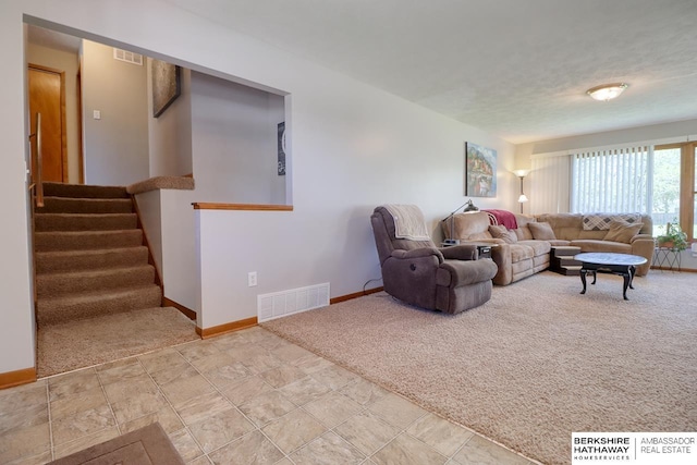 carpeted living room with baseboards, stairs, and visible vents