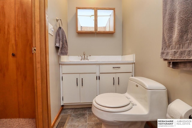 bathroom featuring toilet, visible vents, vanity, and stone finish floor