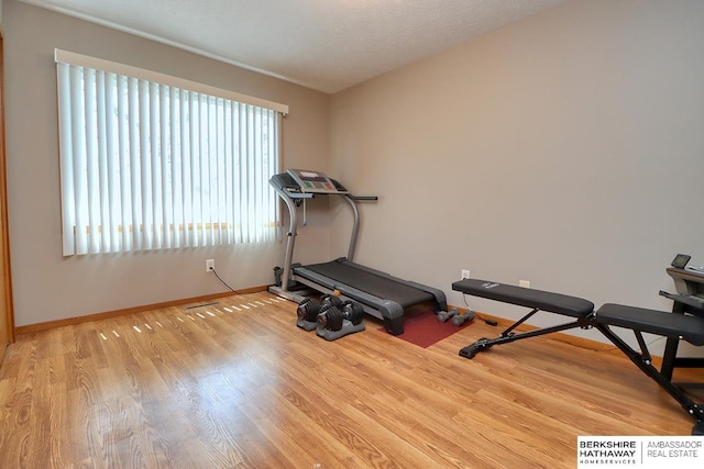 exercise room with light wood finished floors and baseboards