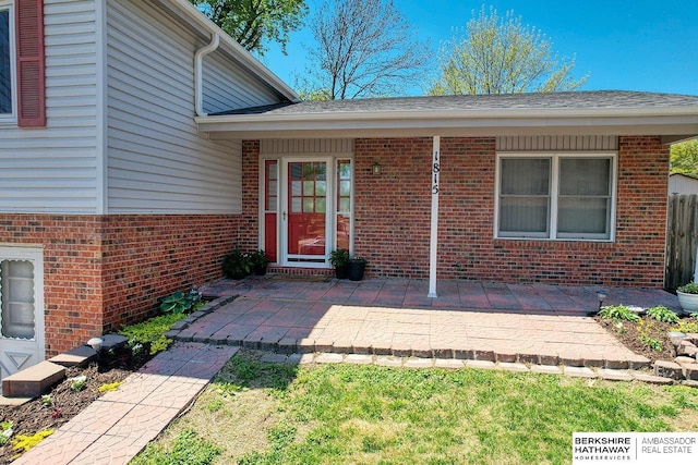 property entrance featuring fence, a patio, and brick siding