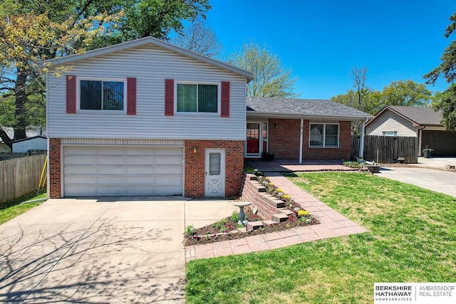 split level home with brick siding, fence, an attached garage, concrete driveway, and a front yard