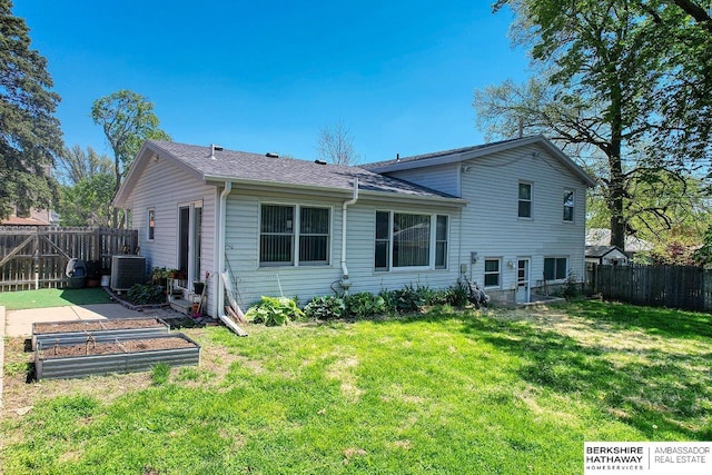back of house with a yard, a fenced backyard, a vegetable garden, and central air condition unit