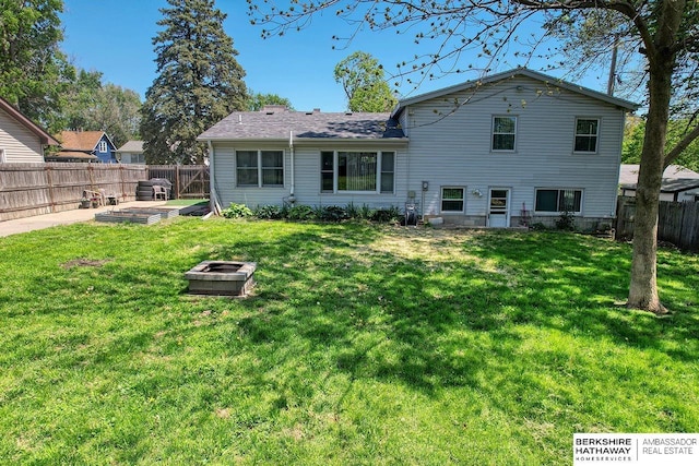 rear view of house with a fire pit, a yard, and a fenced backyard