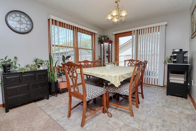 dining room featuring a chandelier, baseboards, and stone finish flooring