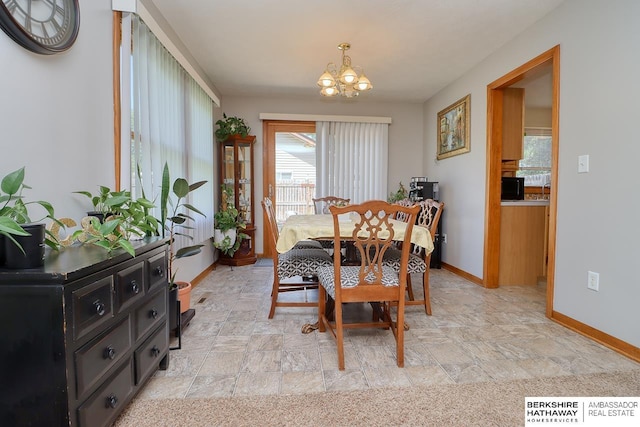 dining room with baseboards, a notable chandelier, and stone finish flooring