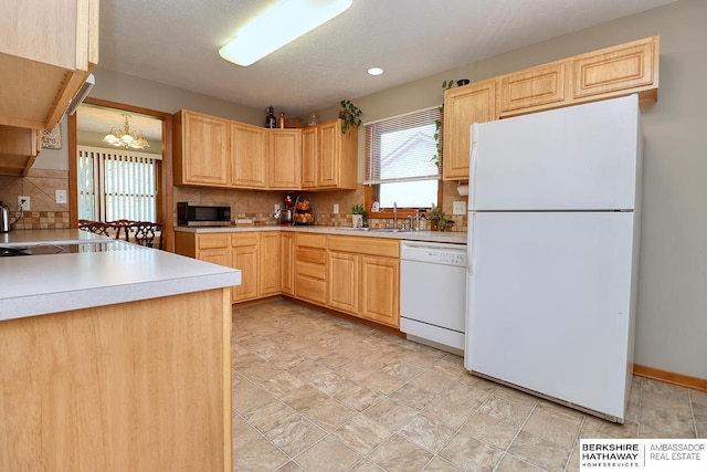 kitchen with white appliances, light brown cabinets, and a sink