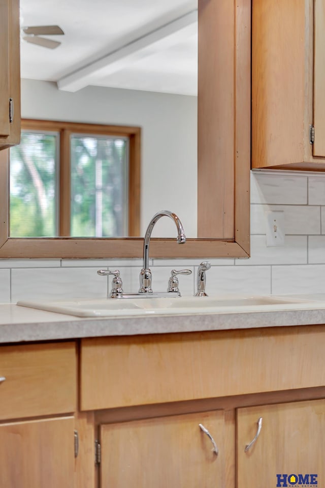 kitchen with light countertops, decorative backsplash, a sink, and light brown cabinetry